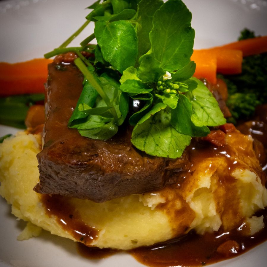Braised beef on mashed potato with watercress and carrots